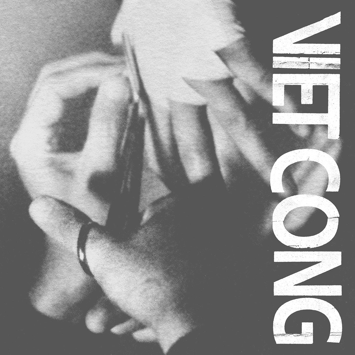 Black and white image of hands holding scissors with 'VIET CONG' text on a dark background