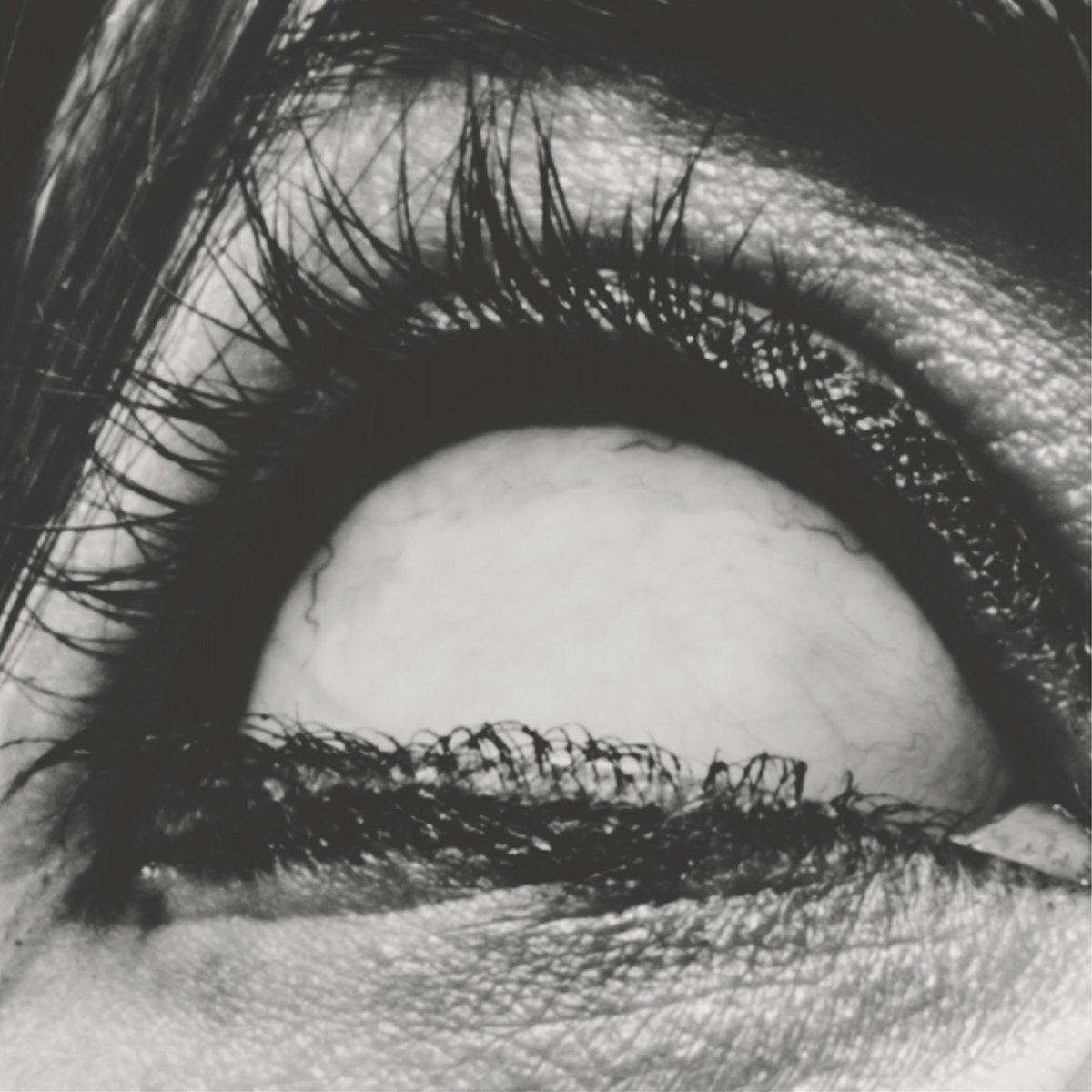 Album cover for A Place To Bury Strangers "Pinned" with a close-up of a person's eye with detailed eyelashes and skin texture.