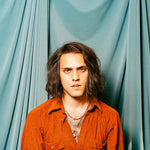 Album cover for Bambara's "Love On My Mind EP" with a person wearing an orange shirt against a teal curtain background