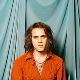 Album cover for Bambara's "Love On My Mind EP" with a person wearing an orange shirt against a teal curtain background