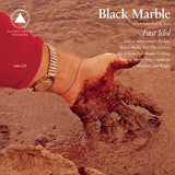 Album cover for 'Fast Idol' by Black Marble with a hand dipping into wet sand, featuring text and logos.