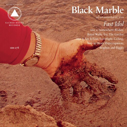 Album cover for 'Fast Idol' by Black Marble with a hand dipping into wet sand, featuring text and logos.