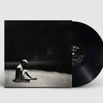 Vinyl record with cover featuring a black and white image of a person sitting on the ground.