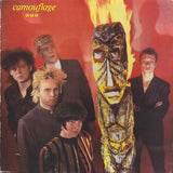 Album cover with five people and a large mask against a red background