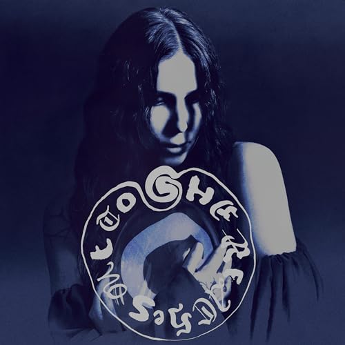 Album cover for 'She Reaches Out To She Reaches Out' by Chelsea Wolfe featuring her posing on a dark-grey and blue background with an emblem.