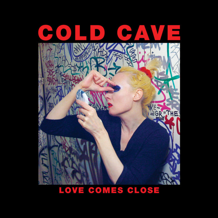 Album cover for 'Love Comes Close' by Cold Cave with a person applying makeup against a graffiti-covered wall.