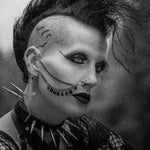 Black and white portrait of a person with dramatic makeup and spike earrings.