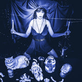 Woman in a dark room with candles, a cat, and mystical objects.