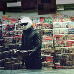 Album cover for Drab Majesty's "Modern Mirror" with a person in a black leather jacket and sunglasses standing in a magazine rack