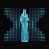 Album cover for Drab Majesty's 'The Demonstration' featuring a figure in a white robe standing between large blue glass blocks on a black background