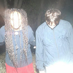 Album cover for 'Derealized' by Jadu Heart featuring two band members wearing blue jackets in a dark, outdoor setting