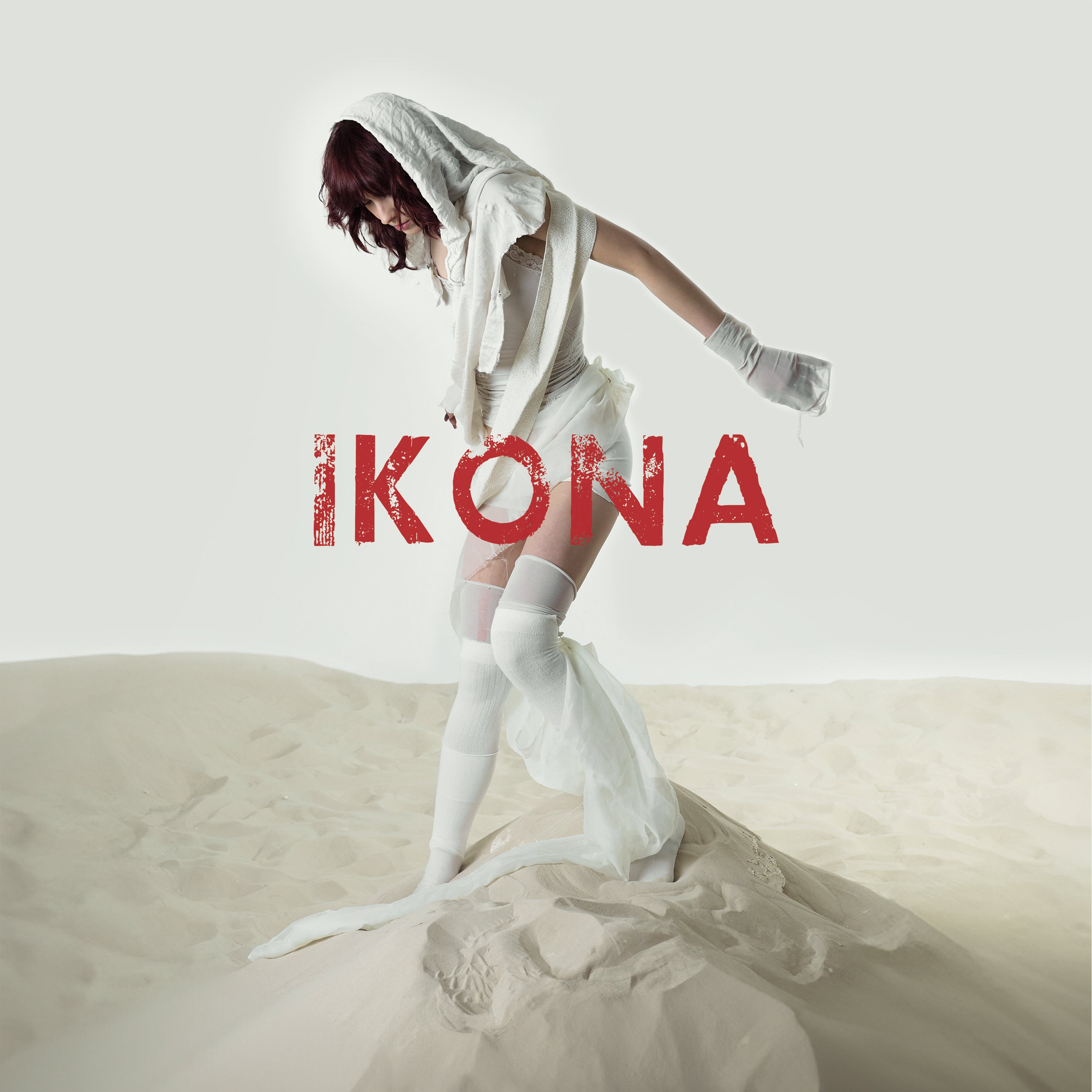 Pardox Obscur album cover with a person in white attire on sand, featuring the word 'IKONA'.