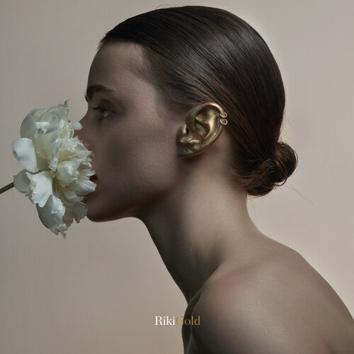 Album cover for Riki Gold showing a woman with a white flower near her face and a gold ear and earrings.