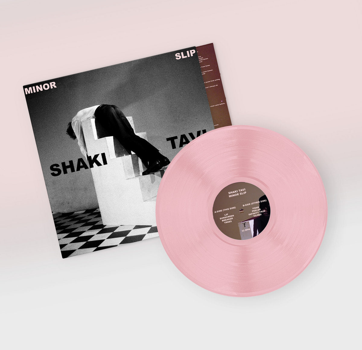 Vinyl record with pink disc and cover featuring 'Shaki' and 'Tavi' on a light background