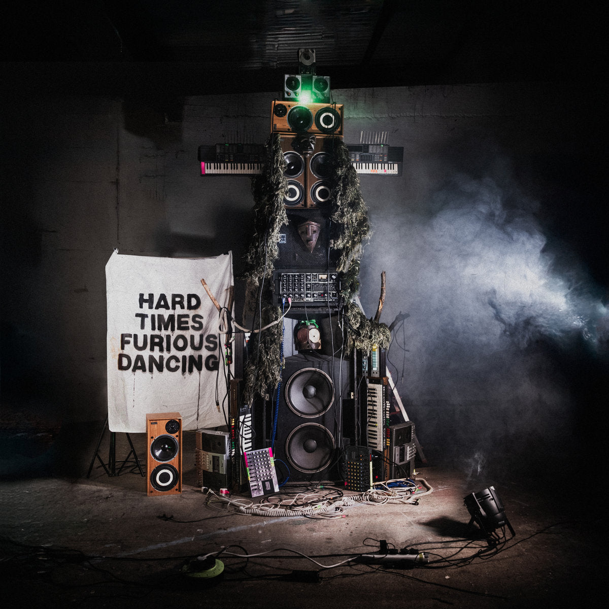 Snapped Ankles - Hard Times Furious Dancing album cover showing an artistic installation with electronic equipment and text in a dark setting