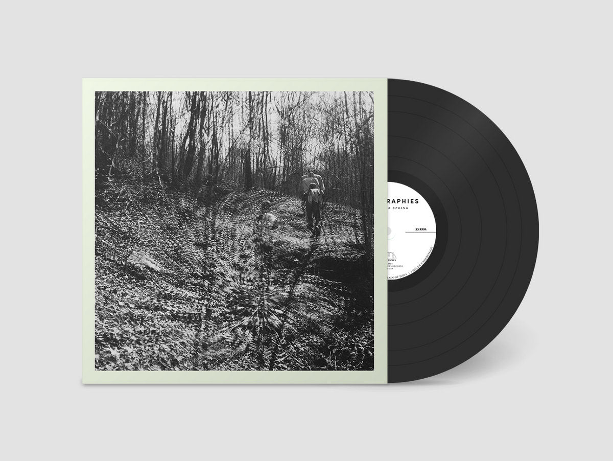 Vinyl record with a black and white cover featuring a forest scene on a gray background