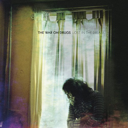 Album cover for 'Lost in the Dream' by The War on Drugs with a person in front of curtains.