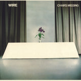 Album cover with a minimalist design featuring a vase with flowers on a table, green curtains, and the title 'Chairs Missing' by Wire.