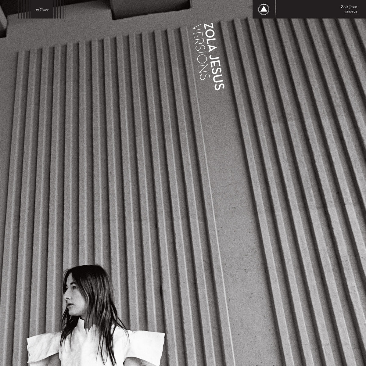 Album cover with a person sitting against a textured wall, featuring 'Zola Jesus * Versions' text.